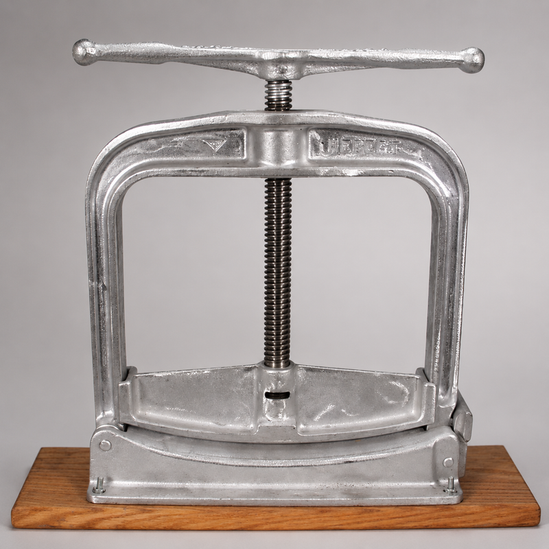 Front view of a Hebert hose clamp secured to mounting brackets on a wooden base