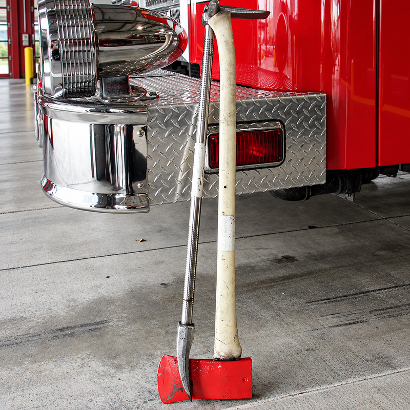 Hooligan entry tool and flat-head axe paired together beside a fire engine
