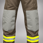 Close-up of INNOTEX RDG20 pants showing gray reinforced knees and lime-yellow and silver reflective bands around the lower legs.