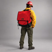 Firefighter wearing the red Strike Team Cascade Hose Pack with black ballistic nylon base and quick-release buckles.