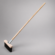 Fire broom with a long hardwood handle, steel shank and flat steel bristles in a wooden head.