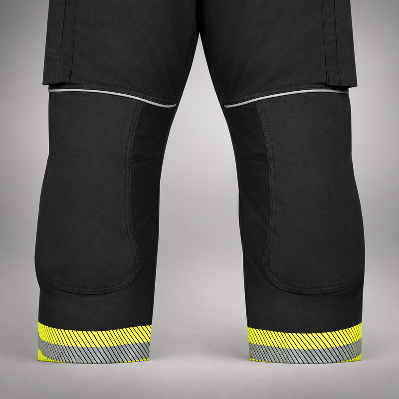 Close-up of black INNOTEX RDG50 turnout pants showing knee panels and segmented reflective trim at the cuffs.