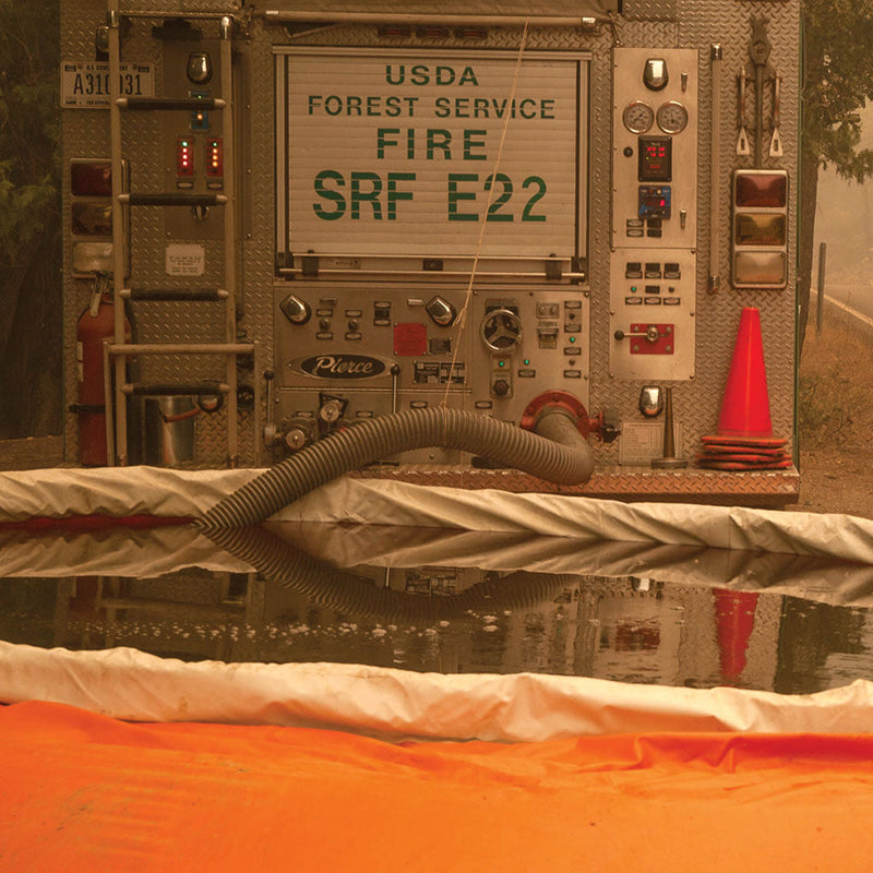 PVC suction hose drafting water from a portable tank into a USDA Forest Service fire engine