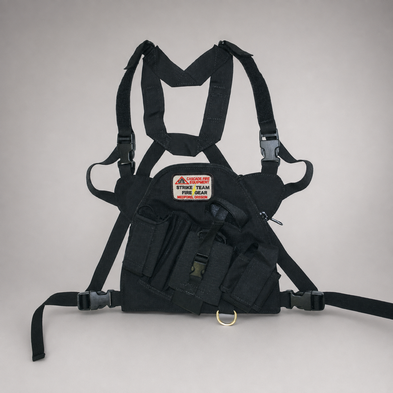 A black firefighter chest rig harness with shoulder straps, waist straps, and a front pouch containing a red and white 'Strike Team Fire Gear' patch, photographed against a neutral light gray background.