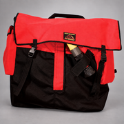 Front view of the red Strike Team Medford Hose Pack showing its buckle-secured flap, black reinforced base and exterior equipment storage.