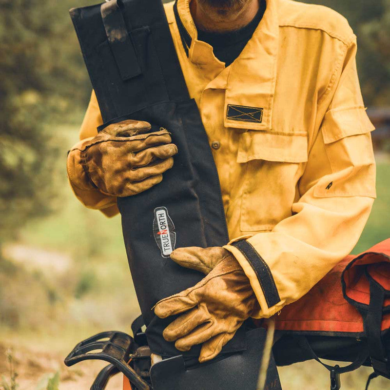 Firefighter holding a True North saw bar cover fitted over a chainsaw bar