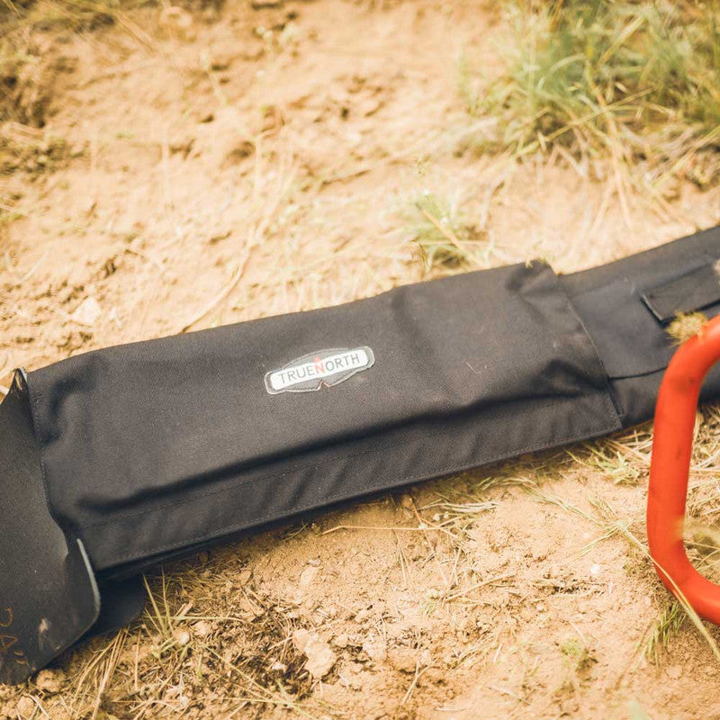 True North saw bar cover lying beside a chainsaw on the ground