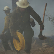 Wildland firefighter carrying a Rogue hoe during fireline operations