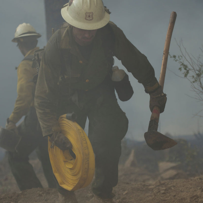 Wildland firefighter carrying a Rogue hoe during fireline operations