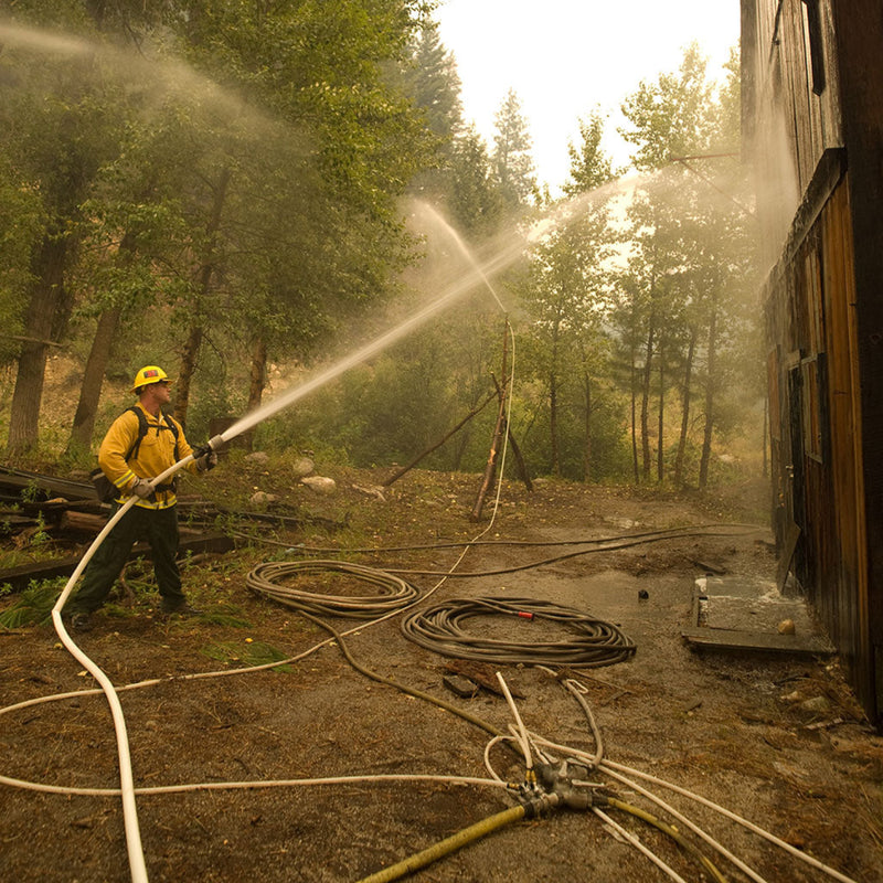 Cascade Fireline Sprinkler spraying water along a wildland fireline