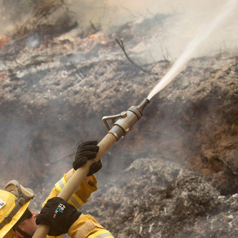 Wildland firefighter using a smooth-bore nozzle to direct a straight water stream