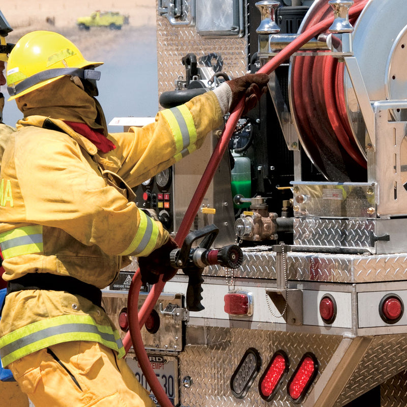 Firefighter deploying red booster hose from an apparatus reel