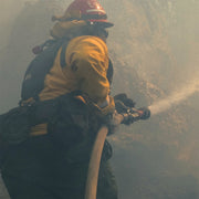 Wildland firefighter using forestry fire hose during fire suppression