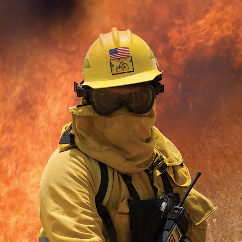 Wildland firefighter wearing Paulson A-TAC protective goggles near an active fir